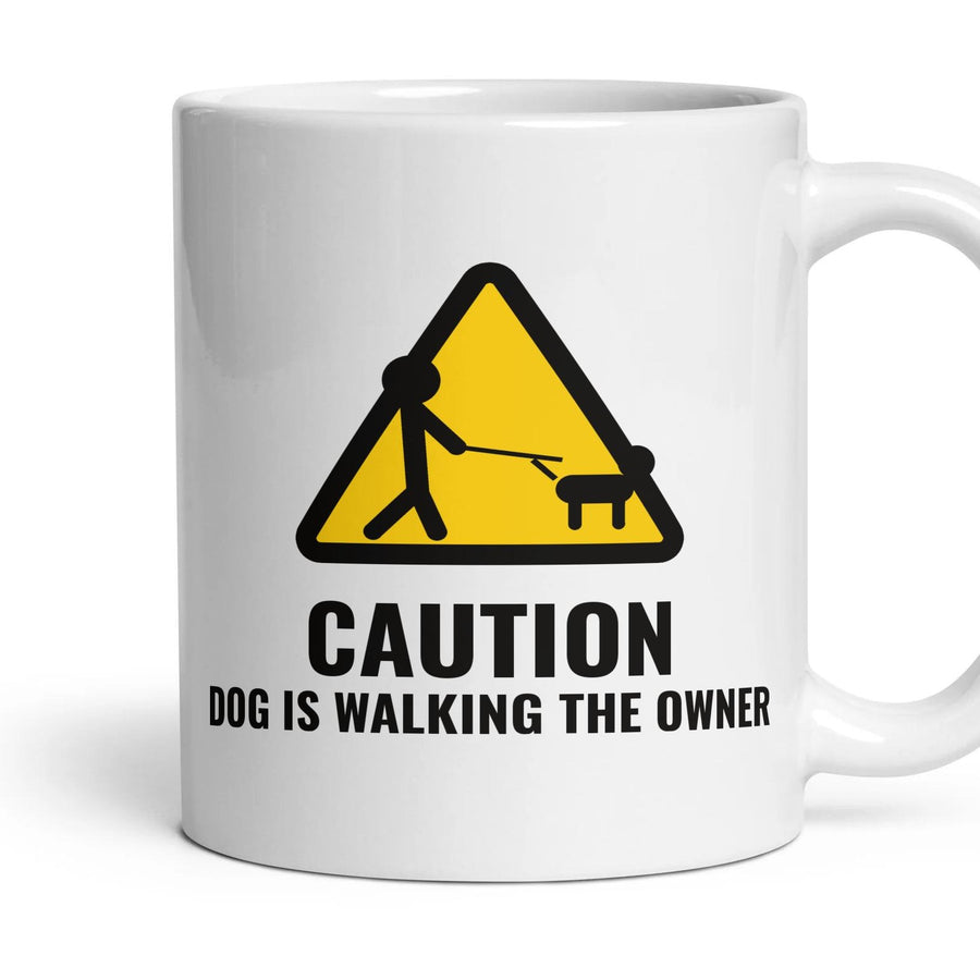 CAUTION: DOG IS WALKING THE OWNER mug, 11oz white ceramic, handle right